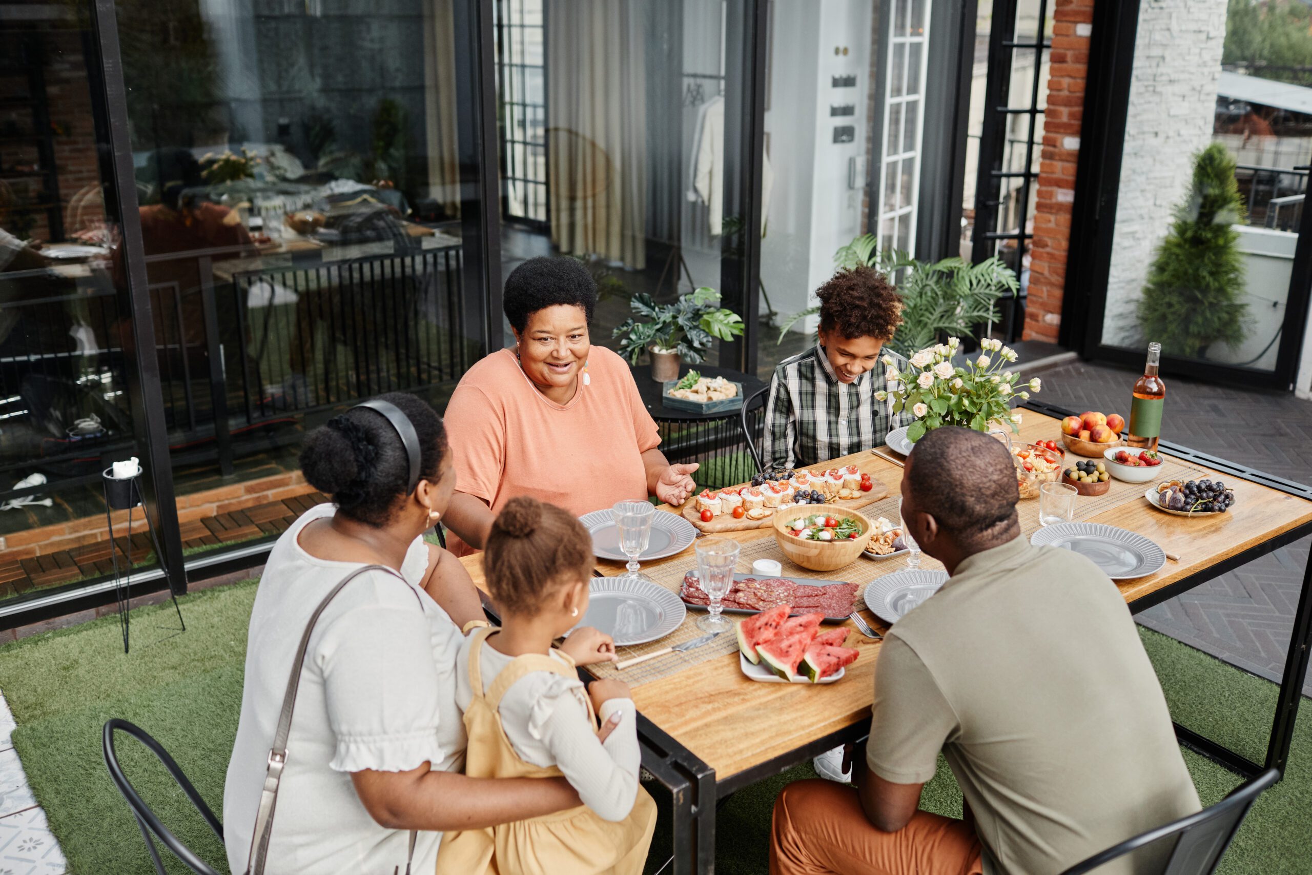 Portrait of multi generation African-American family enjoying dinner party outdoors at terrace, copy space