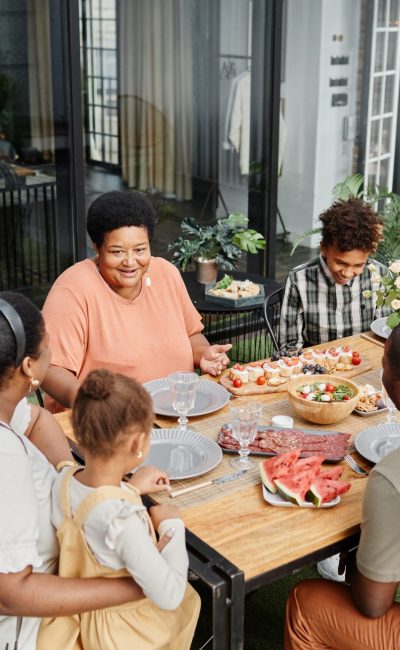 Portrait of multi generation African-American family enjoying dinner party outdoors at terrace, copy space