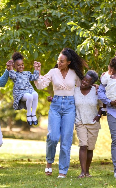 Multi-Generation Family Enjoying Walk In Countryside Together Swinging Granddaughter